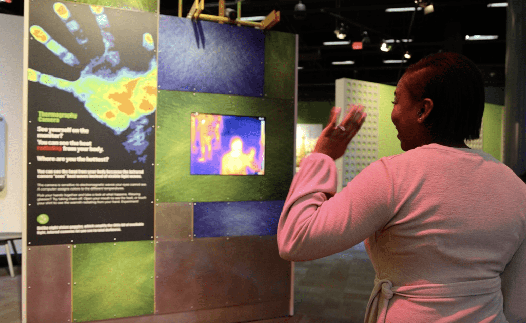 Woman waving a hand at a thermography camera